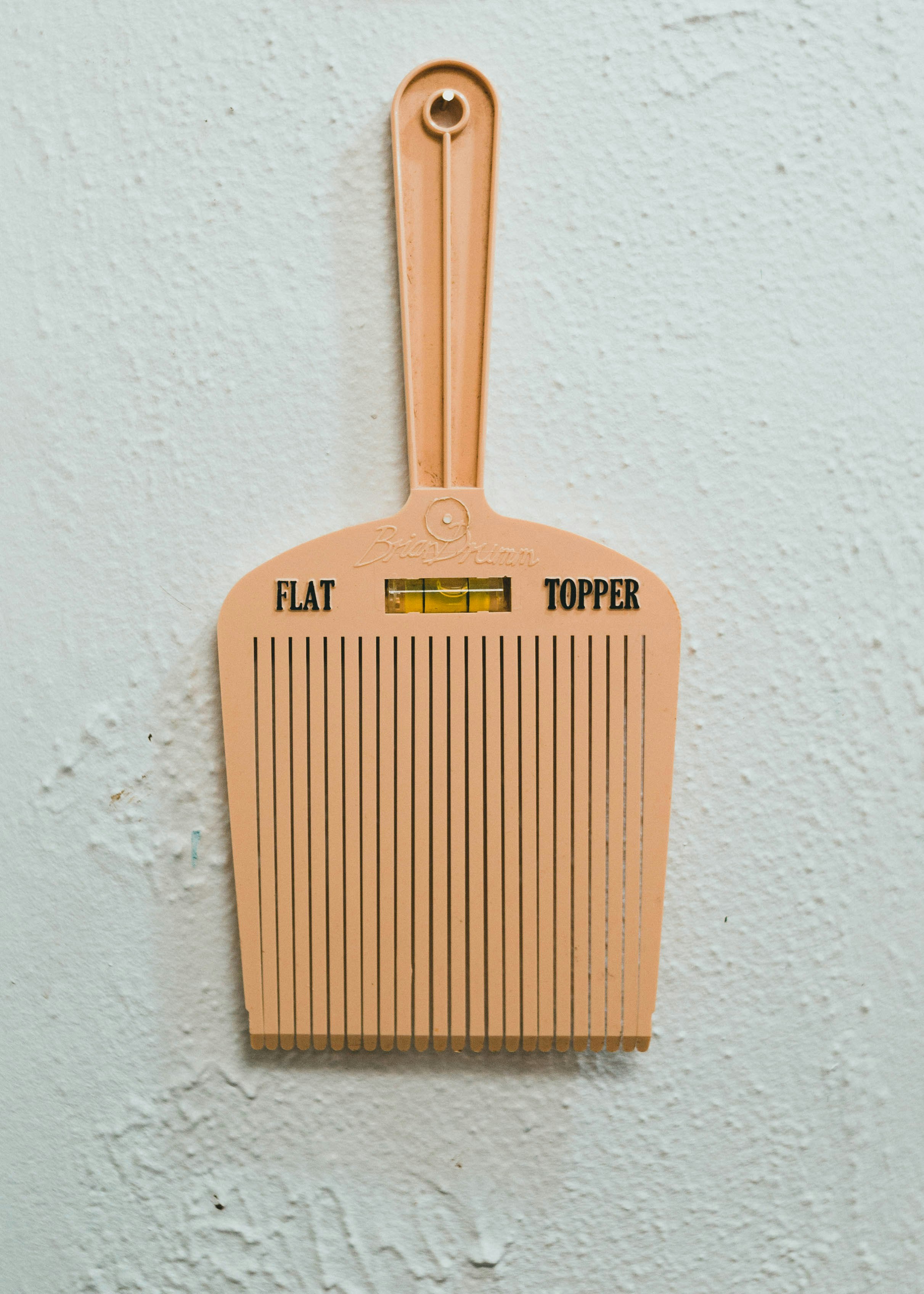 brown wooden hair comb on white painted wall